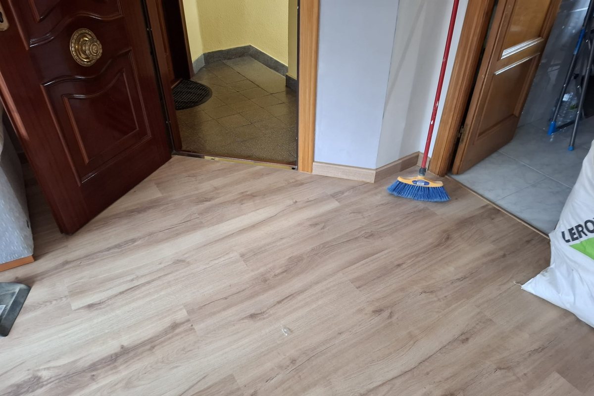 Recibidor con suelo laminado nuevo junto a la puerta de entrada y perfiles de transición